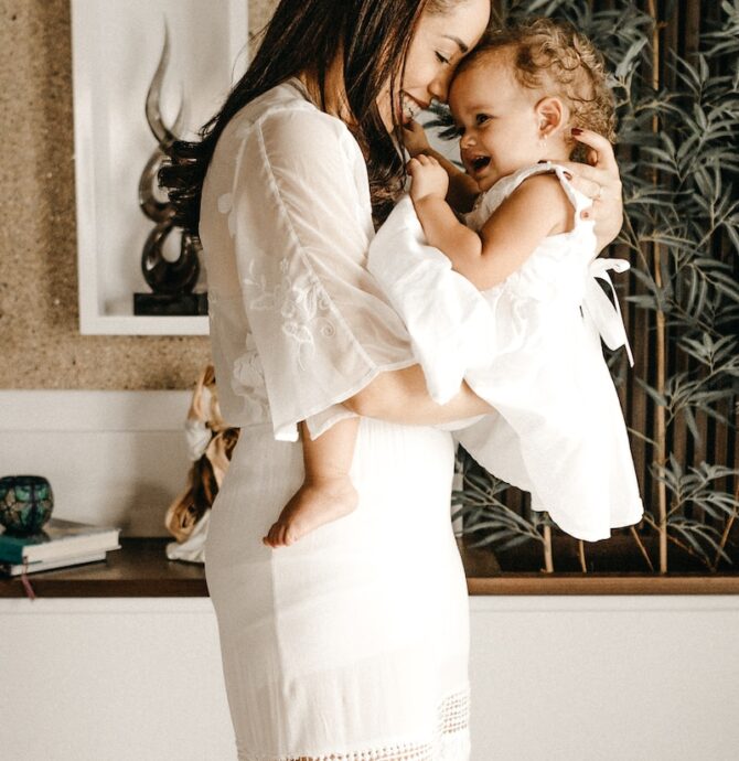 smiling woman in white dress holding toddler